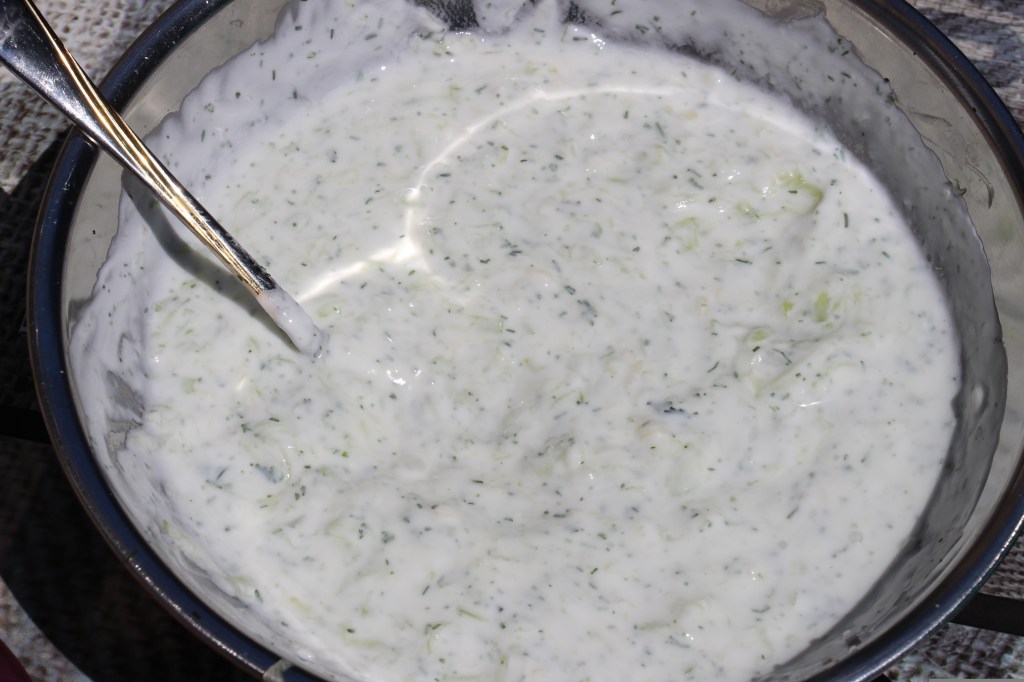 bowl of tzatziki dressing with a metal spoon